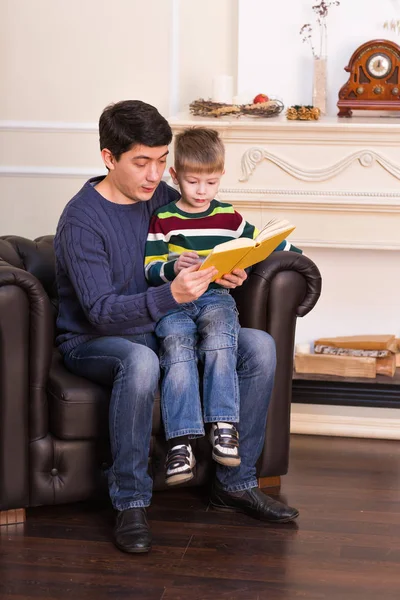 Menino e seu pai ler um livro em casa — Fotografia de Stock