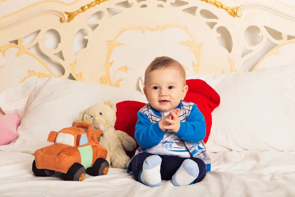 Lindo niño sentado en la cama y jugando con un juguete. Aprendizaje temprano para niños. Actividades con niños en casa . —  Fotos de Stock