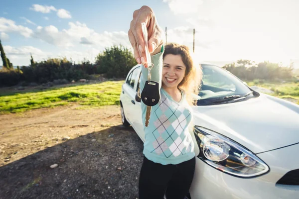 Junge Frau hält Schlüssel für neues Auto und lächelt in die Kamera — Stockfoto