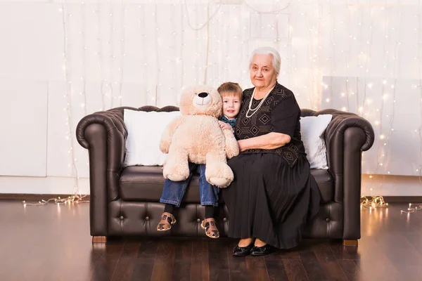 Gamla mormor med sitt barnbarn som sitter på en soffa — Stockfoto