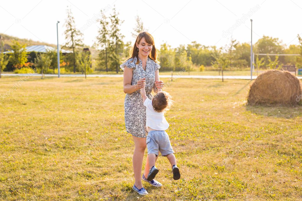 Cute cheerful child with mother play outdoors in park