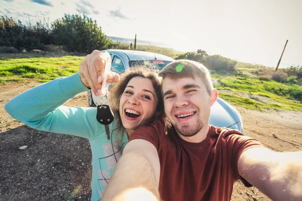 Портрет щасливої красивої пари, що показує ключі, що стоять біля машини — стокове фото