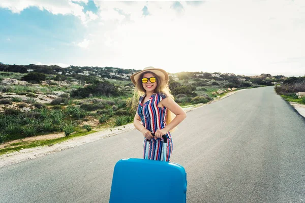 Щаслива усміхнена жінка з блакитною валізою в дорозі — стокове фото