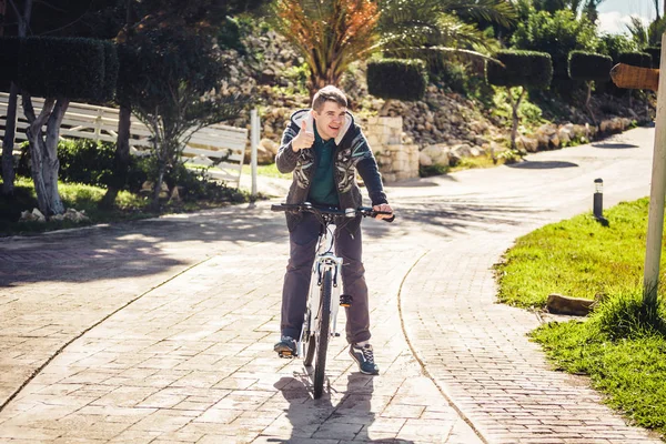 Νεαρό άνδρα ιππασία ποδήλατο στο πάρκο δείχνει τον αντίχειρα επάνω — Φωτογραφία Αρχείου