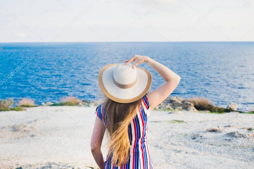 Happy woman enjoying beach relaxing joyful in summer by tropical blue water. Beautiful model happy on travel wearing beach sun hat