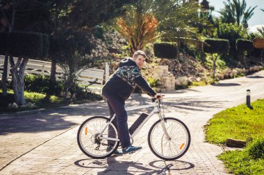 Binilmeye hazır. Kameraya bakarak ve açık havada duran süre gülümseyen bisikletle yakışıklı genç