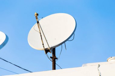 Evin çatısında mavi gökyüzü arkaplanlı uydu anteni ve TV antenleri