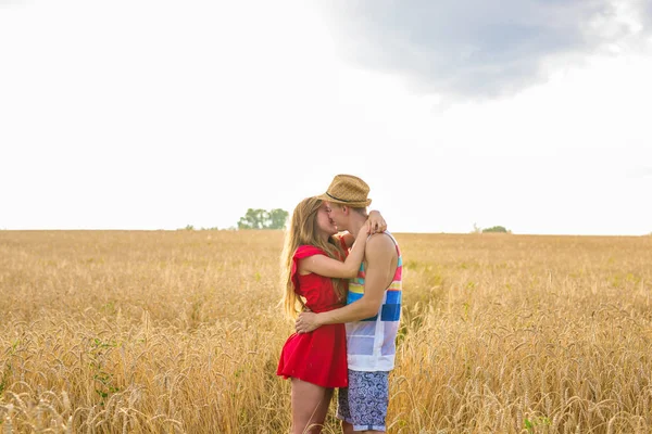 Jovem casal beijando em um campo. Jovem mulher abraçando um homem caucasiano no meio de um campo de trigo e beijando uns aos outros. conceito sobre paixão e amor — Fotografia de Stock