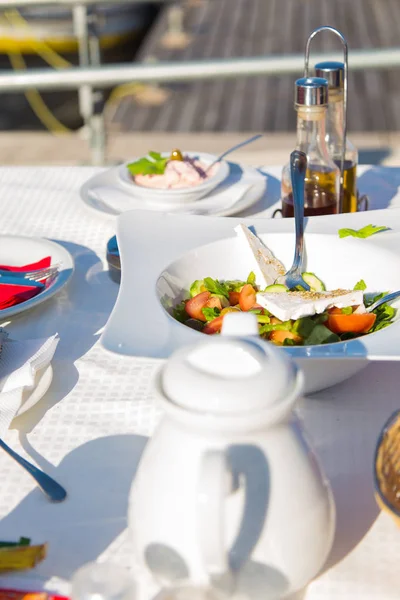 Греческий салат или свежий овощной салат с белым сыром фета на столе в ресторане на пляже . — стоковое фото