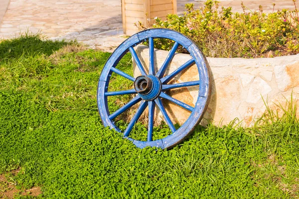 Концепция декора сада - деревянное колесо на фоне зеленой травы — стоковое фото