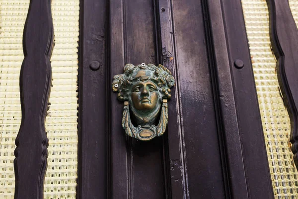 Traditional ornate door handle or knocker against a wooden door — Stock Photo, Image