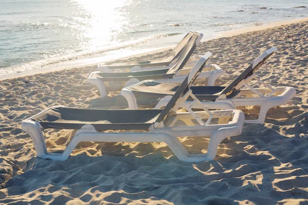 Camas de sol na praia do mar durante o pôr do sol . — Fotografia de Stock
