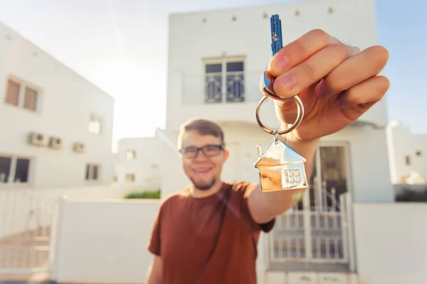 Concepto de inauguración de la casa, bienes raíces, nuevo hogar - Joven con la llave de la casa nueva . —  Fotos de Stock