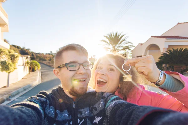 Feliz jovem casal mostrando as chaves de sua nova casa e sorrindo — Fotografia de Stock