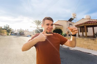 Yeni eve taşınma partisi, gayrimenkul, yeni ev - kavramı holding anahtar yeni evin genç adam.