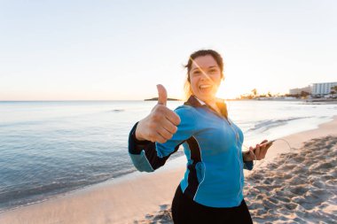 Açık spor, kadın Haritayı başparmak yukarı gülümseyen ve kulaklık ile akıllı telefon tutarak fitness gadget ve insanlar kavramı-.