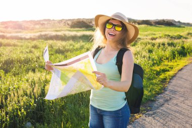 Turizm, seyahat ve yaz kavramı - mutlu kadın yolcunun sırt çantası ile yön bulmak için harita denetler..