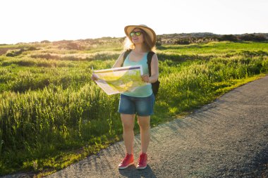 Turizm, seyahat ve yaz kavramı - mutlu kadın yolcunun sırt çantası ile yön bulmak için harita denetler..