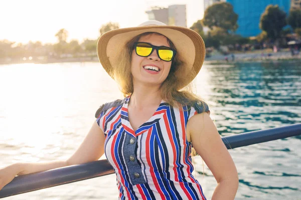 Zomer vakantie, vakantie, reizen en mensen concept - glimlachend jonge vrouw dragen zonnebril en hoed op strand over zee achtergrond — Stockfoto