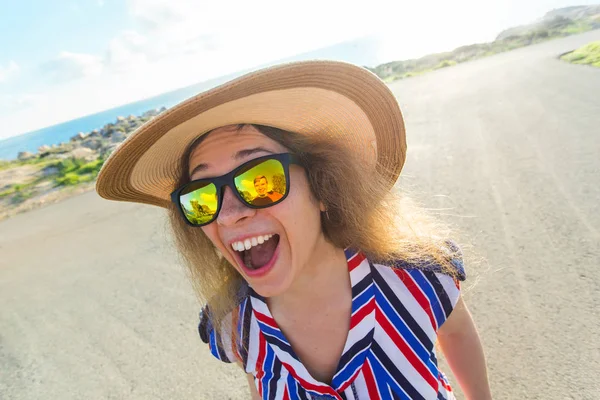 Літо, свято, селфі та концепція відпустки - молода жінка робить смішне обличчя в літній день в капелюсі та сонцезахисних окулярах — стокове фото