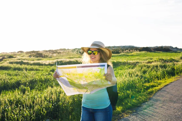 Turismo, viajes y concepto de verano - Mujer feliz viajero con mochila comprueba mapa para encontrar direcciones . — Foto de Stock