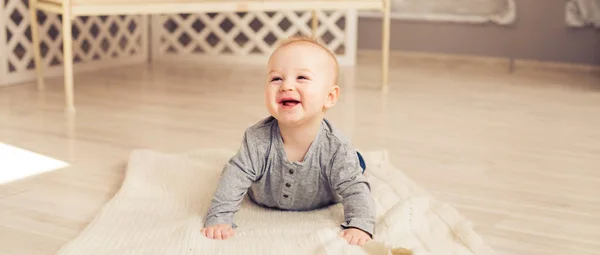 Adorable laughing baby boy in sunny bedroom. Newborn child relaxing. Nursery for young children.Family morning at home. Little kid lying on tummy