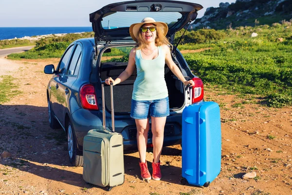 Cestování, letní prázdniny a dovolené koncepce - mladá žena s kufry na cestě autem. — Stock fotografie