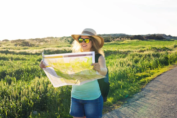 Turismo, viajes y concepto de verano - Mujer feliz viajero con mochila comprueba mapa para encontrar direcciones . — Foto de Stock
