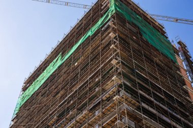 Mavi gökyüzüne karşı inşaat halindeki vinç ve bina