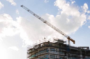 Mavi gökyüzüne karşı inşaat halindeki vinç ve bina