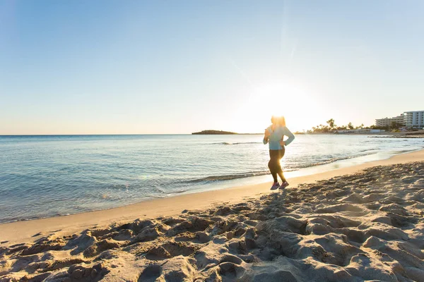 Jonge gezonde levensstijl fitness vrouw lopen bij sunrise beach — Stockfoto