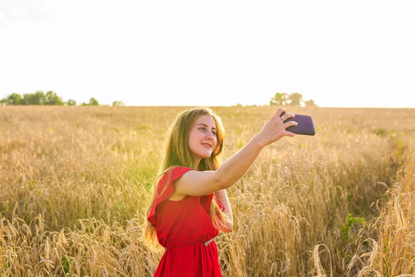 Technologie, zomer vakantie, vakantie en mensen concept - jonge vrouw nemen selfie glimlachen door smartphone op granen veld. — Stockfoto