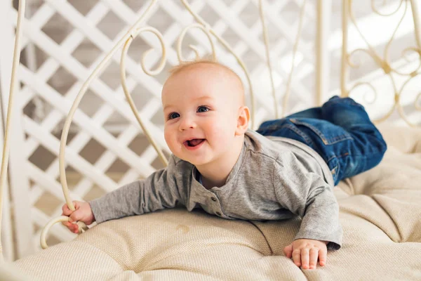 Adorable niño riendo en el dormitorio soleado. Niño recién nacido relajándose. Guardería infantil para niños pequeños.Mañana familiar en casa. Niñito acostado boca abajo —  Fotos de Stock