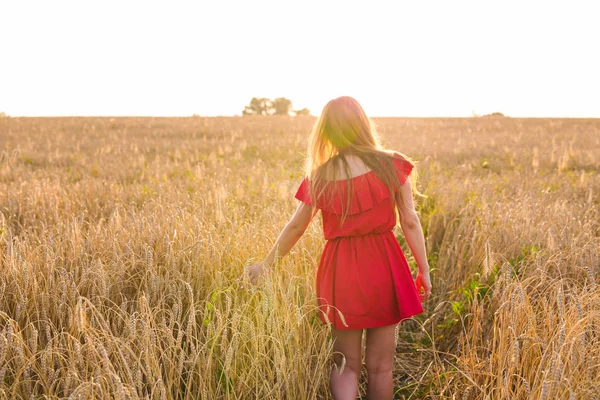 Mujer joven vestida de rojo en el campo de verano, vista trasera —  Fotos de Stock
