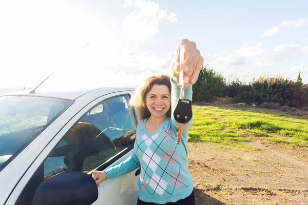 auto business, car sale, consumerism and people concept - happy woman holding new car key outdoor