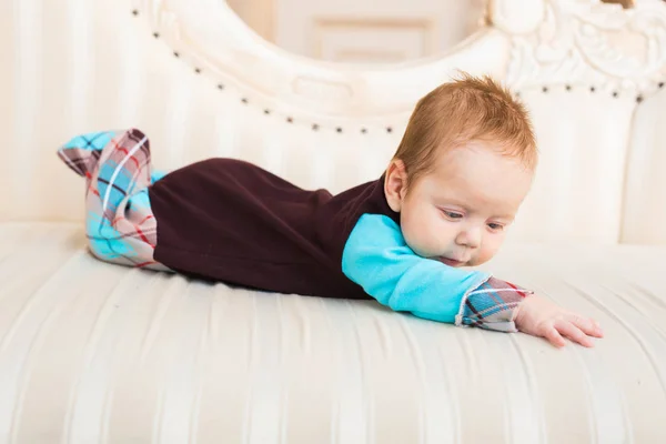 Adorable niño con el pelo rojo y los ojos azules. Recién nacido lyling en sofá . — Foto de Stock