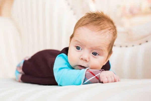 Retrato de primer plano del niño con el pelo rojo y los ojos azules. Recién nacido lyling en sofá . — Foto de Stock