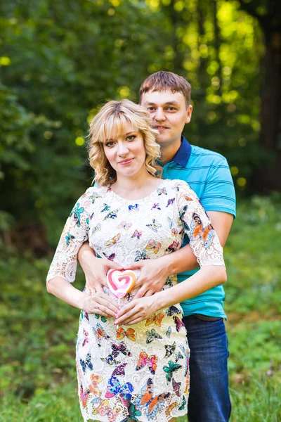 Счастливая молодая беременная пара, обнимающая природу — стоковое фото