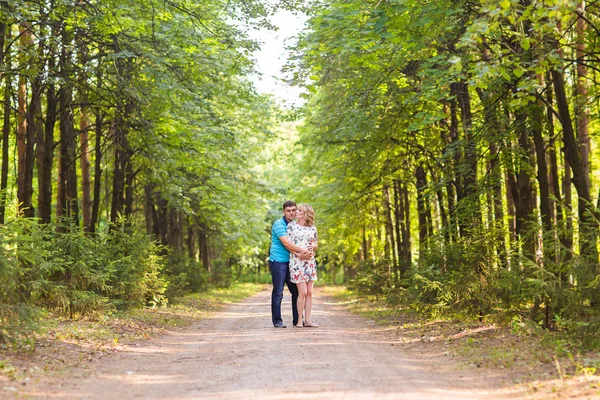 Feliz joven embarazada pareja abrazándose en la naturaleza —  Fotos de Stock