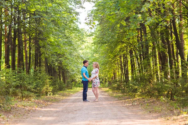 Glad ung gravid kvinna med maken promenader i en park — Stockfoto