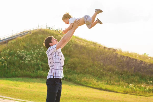 Jeune père heureux tenant bébé fils dans les mains sur sa tête à l'extérieur — Photo