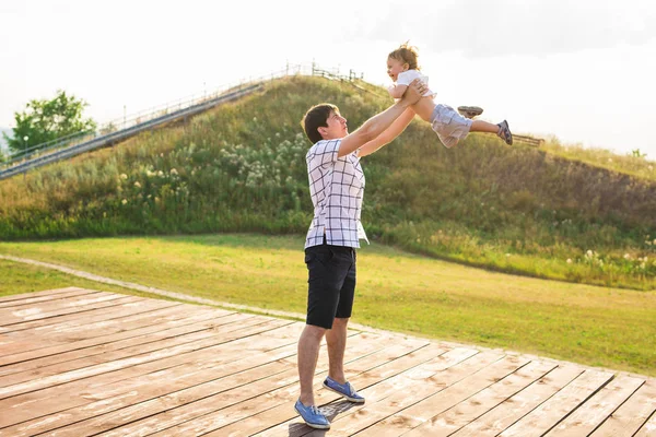 Heureux père tenant le petit enfant dans les bras, jetant bébé dans l'air. concept de famille heureuse, paternité — Photo