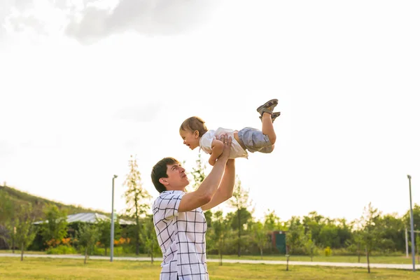 Heureux père tenant le petit enfant dans les bras, jetant bébé dans l'air. concept de famille heureuse, paternité — Photo