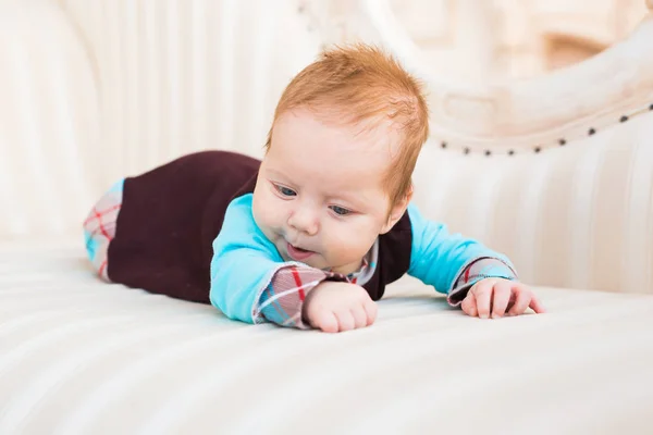 Retrato de primer plano del niño con el pelo rojo y los ojos azules. Recién nacido lyling en sofá . —  Fotos de Stock