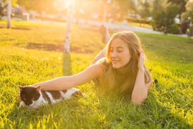 Evcil hayvan ve sahibi kavramı - çim bir kedi ile oynarken güzel kız.