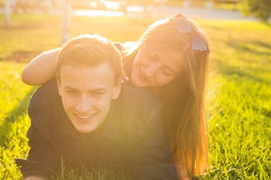 Çimlere uzanmış ve gülümseyen genç bir çift ile eğlenceli ve sevgi kavramı