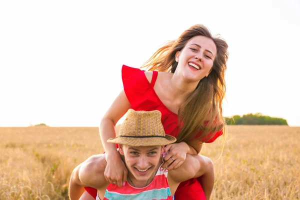 Couple heureux s'amuser en plein air sur le terrain. Concept de liberté. Giggyback . — Photo