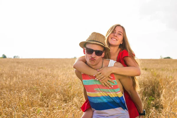 Casal feliz se divertindo ao ar livre no campo de trigo. Rindo Família alegre juntos. Conceito de Liberdade. Piggyback. — Fotografia de Stock