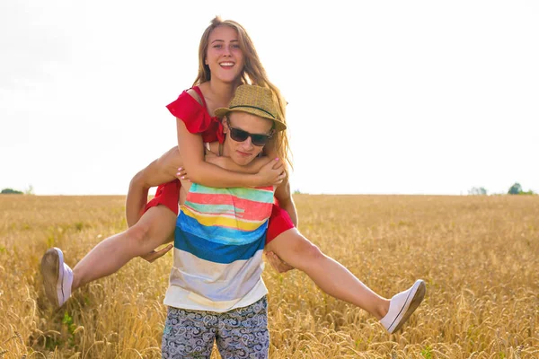 Casal feliz se divertindo ao ar livre no campo de trigo. Rindo Família alegre juntos. Conceito de Liberdade. Piggyback. — Fotografia de Stock