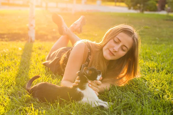 애완 동물 및 소유자 개념-풀밭에서 고양이 함께 재생 하는 아름 다운 소녀. — 스톡 사진